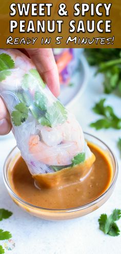 a person dipping sauce into a bowl with shrimp and cilantro on it,