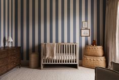 a baby's room with striped walls and furniture