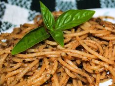 a plate with noodles and basil on top, ready to be eaten or served for lunch