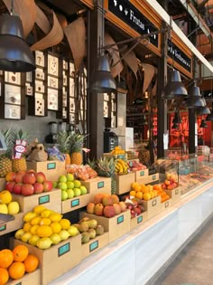 an outdoor market with lots of fresh fruits and vegetables on display in boxes, hanging from the ceiling