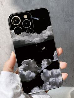 a person holding up a phone case with clouds in the sky and moon on it