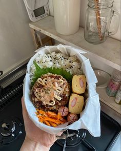 a person holding a bowl filled with food on top of a stovetop next to an oven