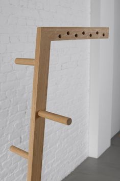 a wooden stand with holes in it against a white brick wall