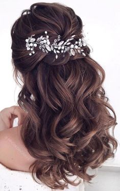 a woman with wavy hair wearing a bridal headpiece made of pearls and leaves