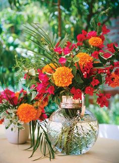 vases filled with flowers sitting on top of a table next to potted plants