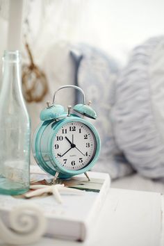 a blue alarm clock sitting on top of a table next to a bottle and starfish