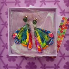 Showcase your love and appreciation for all things bright and cheery with these darling little butterfly wing earrings.  Watch as they appear to flutter to-and-fro and observe how they seemingly spread joy with every step.  A perfect gift for book worms, food connoisseurs and gardeners alike - these wings are hand sculpted from polymer clay and given their vibrant hues with acrylic paint.  Once dry everything is sealed with varnish and ready for takeoff. These wings are offered in three differen Caterpillar Earrings, Art Teacher Aesthetic, Teacher Character, Toothpaste Kisses, Butterfly Book, Teacher Earrings, Earring Inspo, Crazy Art, Shrinky Dink