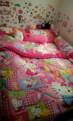 a bed with hello kitty comforter and pillows in a room that has hello kitty wallpaper on the walls