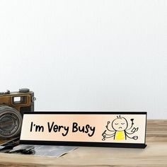 a wooden sign that says i'm very busy next to an old camera