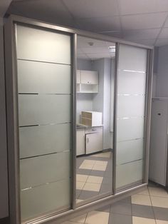 an empty room with mirrored doors and white cabinets