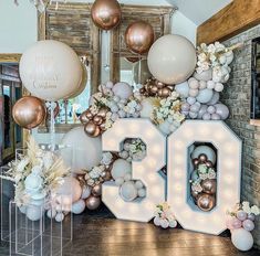 balloons and flowers decorate the entrance to a 30th birthday party in pink, gold and white