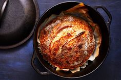 a loaf of bread sitting in a skillet on top of a wooden table next to a hat