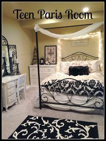 a bed room with a neatly made bed and white dressers, mirror and lights