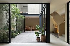 an open room with plants and stairs leading to the upper floor, along with potted plants on either side of the glass door