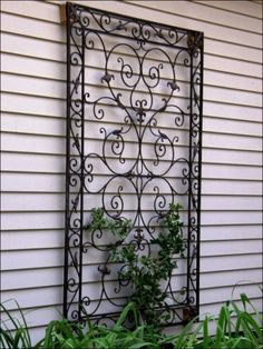 an iron screen with plants in it on the side of a house