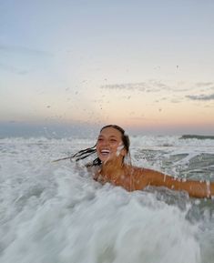 a woman smiles as she rides the waves on her surfboard in the ocean at sunset