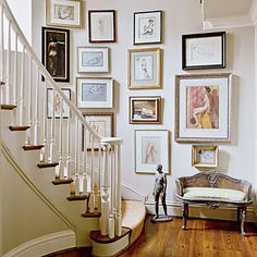 a staircase with many framed pictures on the wall and a figurine sitting next to it