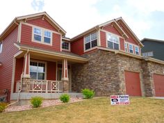 a red brick house with a for sale sign in front of it and two garages on the other side