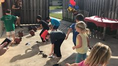 a group of children playing with basketballs on the ground in front of a fence