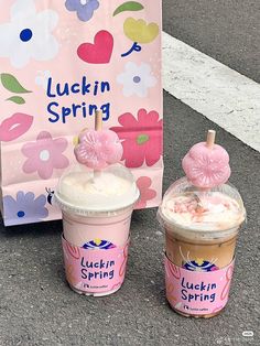 two cups of ice cream sitting on the ground next to a sign that says lucky spring