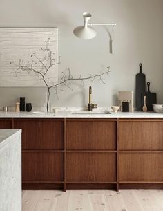 a kitchen with wooden cabinets and marble counter tops, white walls and wood flooring