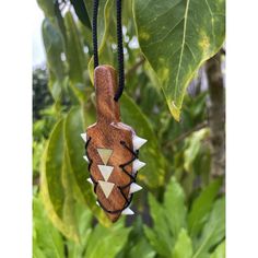 a wooden necklace hanging from a tree with green leaves in the backgroung