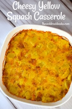 cheesy yellow squash casserole in a white dish on a wooden table