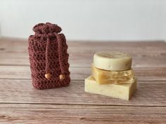 two pieces of soap sitting next to each other on top of a wooden table with a crocheted bag