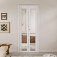 an empty living room with white walls and pictures hanging on the wall above the door