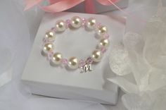 "Flower Girl Bracelets personalized with her monogram initial make a pretty gift for any little girl in your bridal party. Child size FAUX pearl bracelets have alternating Sparkly Pink Crystal beads between some of the faux pearl and a little dainty monogram charm. Add a beautiful gift box with or without a Beautiful Flower Girl Thank You Card Or Flower Girl Proposal Card for the perfect packaging. It is handmade with high-quality materials that will last. All of our bracelets can be made for in Elegant Personalized Stretch Bracelet For Gifts, Elegant Personalized Stretch Bracelet As A Gift, Elegant Personalized Stretch Bracelet Gift, Elegant Personalized Stretch Bracelet As Gift, Elegant White Name Bracelet For Birthday, Elegant White Bracelets, Personalized Pink Pearl Bracelet For Birthday, Personalized Pink Charm Bracelet For Wedding, Hypoallergenic White Bracelet For Bridesmaids