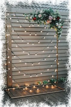 a wedding arch decorated with flowers and greenery is lit up by fairy lights on the side