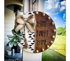 a wooden sign that says home sweet home with a bow hanging on the front door