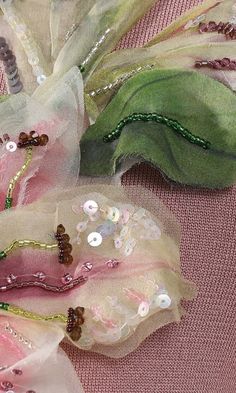 three pieces of fabric with beaded and sequins on them sitting on a pink surface