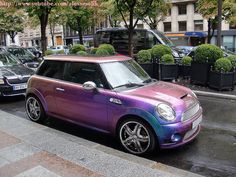 a purple and blue car is parked on the side of the road in front of some cars