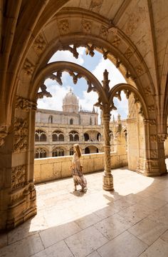 a woman is walking through an archway in the middle of a building with arches and pillars