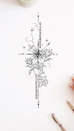 a drawing of a compass with flowers on it next to some pens and pencils