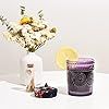 a vase filled with white flowers next to a jar of blackberries and lemons