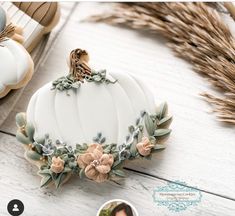 a white pumpkin decorated with flowers sitting on top of a table next to some cookies