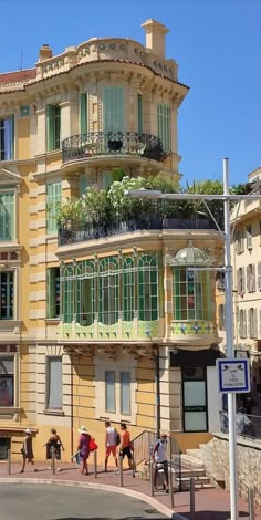 people walking on the sidewalk in front of a building with balconies and windows