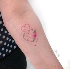 a woman's arm with two hearts and a flower tattoo on the left forearm