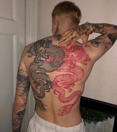 a man with dragon tattoos on his back and arms, standing in front of a door