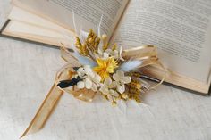 an open book on a table with flowers and feathers attached to it's handle