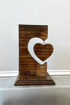 a wooden sign with a heart on it sitting on top of a metal shelf next to a white wall