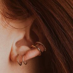 a close up of a woman's ear with two gold hoops on it