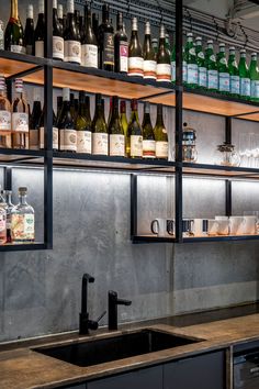 the shelves are full of bottles and glasses on the wall above the sink in the kitchen