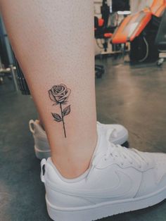 a woman's foot with a rose tattoo on her left leg and white sneakers