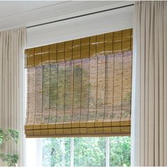 the window is covered with bamboo blinds and drapes, along with a potted plant