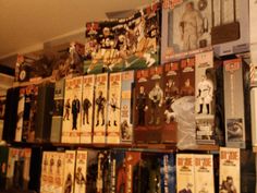 a wall full of star wars action figures and movies on display in a store or office