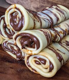 chocolate covered rolled up pastry sitting on top of a wooden cutting board