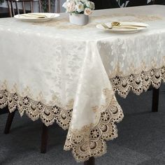 the table cloth is white with gold trimmings and has two place settings on it